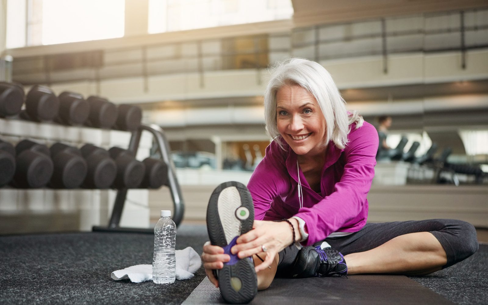 Frau dehnt sich entspannt und selbstbewusst im Fitnessstudio